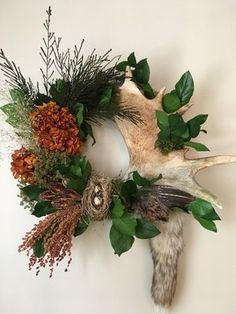 a deer's antler head is adorned with flowers and greenery on the wall