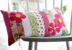 a white chair with a pink flowered pillow on it's back and a yellow button in the center