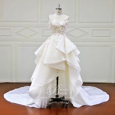 a wedding dress is displayed on a mannequin in front of a white wall