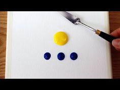 a person is holding a paintbrush and painting circles on a piece of white paper