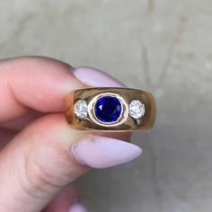 A vintage French three stone gypsy ring, featuring a round cut natural sapphire weighing approximately 0.57 carats. Two old mine cut diamonds weighing approximately 0.15 carats each flank the center stone. This ring was handcrafted in 18k yellow gold circa 1965, and bears French hallmarks.
The measurements of the sapphire are approximately 5.20mm x 5.30mm x 3.07mm. The band width ranges from 5.70mm – 9.19mm.
This ring is currently size 6, and can be resized at no extra cost.
If you have any ques Three Stone Sapphire Ring, Estate Diamond Jewelry, Vintage Sapphire Ring, Ring Jewellery Design, Sapphire Band, Three Stone Ring, 18k Yellow Gold Ring, Three Stone Rings, Natural Sapphire