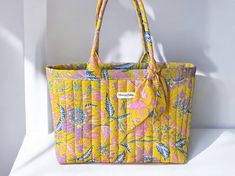 This yellow floral tote bag in quilted batik fabric with its bohemian spirit will accompany you every day and on all your escapades, whether in town or out for a weekend stroll, thanks to its generous size, practical and chic. It's handmade in France in my workshop from hand-printed Balinese Batik cotton fabrics. PRODUCT DETAILS : 🇫🇷 French craftsmanship * Standard size : 40x30x10 cm  /  15.8x11.8x4.8in   Large size : 40x30x15cm  /   15.8x11.8x 5.9in * 100% cotton Batik hand-printed in Bali In Everyday Yellow Floral Print Bags, Summer Quilted Bag, Quilted Summer Bags, Quilted Bags For Everyday Summer Use, Yellow Floral Print Bag For Daily Use, Yellow Floral Print Bags For Daily Use, Yellow Floral Print Everyday Bag, Bohemian Tote Shoulder Bag With Floral Print, Bohemian Floral Print Tote Shoulder Bag