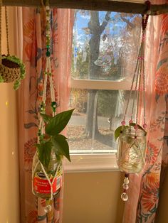 two vases with plants hanging from them in front of a window