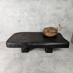 a small wooden bowl sitting on top of a black bench with a leather cover over it