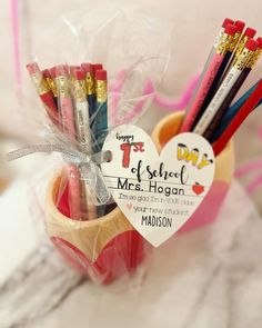 a cup filled with lots of pencils on top of a white tablecloth next to a valentine's day card