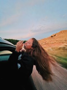 a woman with long hair riding in the back of a car