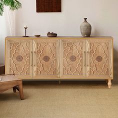 a large wooden cabinet sitting in a living room next to a vase and table on top of a rug