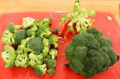 broccoli florets are sitting on a red plate next to a knife