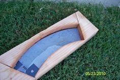 a small wooden box with a knife in it on the grass next to a sidewalk