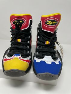 POWER RANGERS QUESTION MID SHOES BASKETBALL-INSPIRED QUESTION MID SHOES WITH A POWER RANGERS DESIGN "Megazord Battle Mode!" It's time to transform in these Reebok Question Mid shoes. The colours, graphics and details are all inspired by Power Rangers character the Mighty Morphin' Megazord. Assemble your crew and go save the world. You've got the shoes for it. Lace closure Synthetic upper Lightweight feel Power Rangers collaboration Soft Hexalite hexagonal cushioning Textile lining EVA midsole Ab Power Ranger Sneakers, Power Rangers Design, Reebok Question Mid, Reebok Question, Power Rangers Megazord, Mid Shoes, Shoes Basketball, Save The World, The Mighty