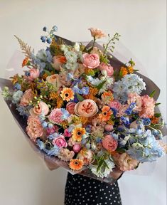 a woman holding a large bouquet of flowers in her hands and wearing a polka dot dress