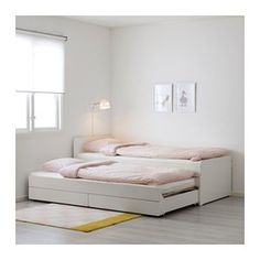 two beds in a room with white walls and flooring, one has pink sheets on it