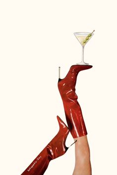 a woman's legs in red rubber boots holding a martini glass