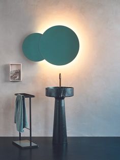 two circular lights on the wall next to a table with a towel rack and chair