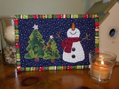 a wooden table topped with a snowman next to a lit candle