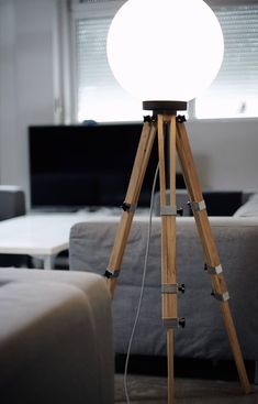 a tripod light sitting on top of a wooden stand in front of a couch