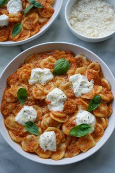 two bowls filled with pasta and cheese on top of a table