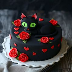 a black cake decorated with red roses and a cat