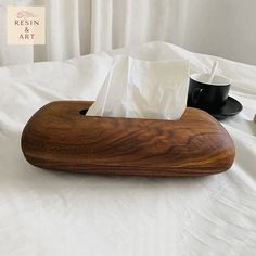 a tissue dispenser sitting on top of a bed next to two cups