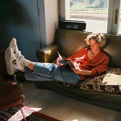 a woman sitting on top of a couch next to a window