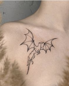 a woman's chest with a small tattoo of a flying bird on the left side