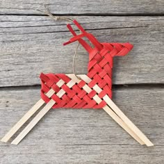 an ornament made out of sticks with a red and white deer on it