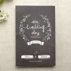 the wedding day is written in chalk on a blackboard with floral wreaths and ribbons