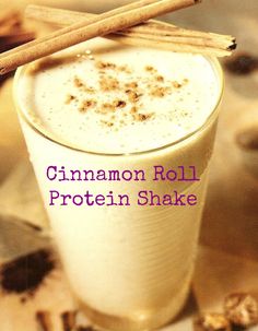 cinnamon roll protein shake in a glass with cinnamon sticks sticking out of the top and bottom