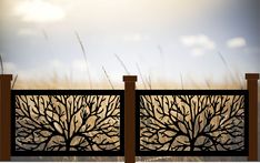 an iron fence with trees on it in front of the sky and grass behind it