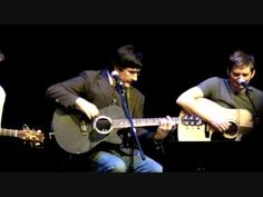 two men are playing guitars and singing into microphones