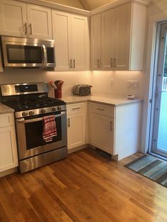 an empty kitchen with stainless steel appliances and wood flooring is shown in this image