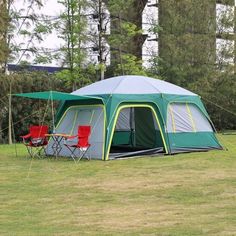 a tent set up in the middle of a field with two chairs and one table