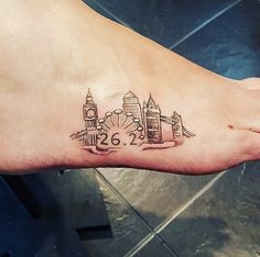 a small tattoo on the foot of a person with a clock tower in the background