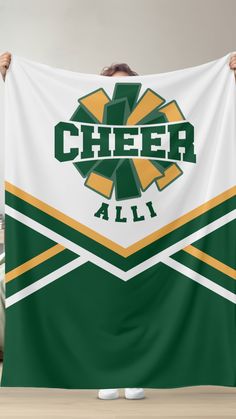 a man holding up a green and yellow cheer flag with the word cheer all over it