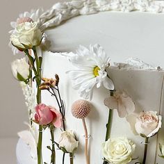 a close up of a cake with white frosting and flowers on the top layer