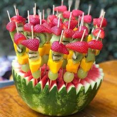 a watermelon bowl filled with fruit and skewered on toothpicks