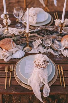 the table is set with plates, silverware and seashells for an elegant touch