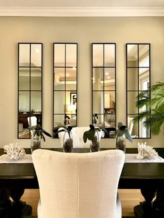 a dining room table with chairs and mirrors on the wall