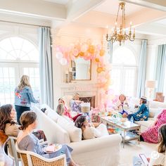 a group of people sitting around in a living room with balloons on the wall and furniture