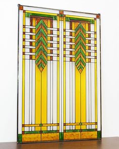 an art deco stained glass window with green and yellow designs on the sides, mounted on a wall