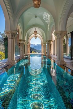 an indoor swimming pool with blue water and stone arches on the sides, surrounded by columns