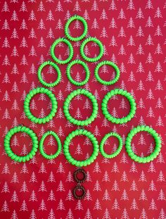 a christmas tree made out of green rings on a red background with small white trees