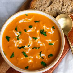 a bowl of carrot soup with bread on the side