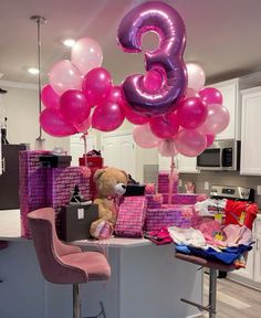 balloons and presents are on the counter in this kitchen with a teddy bear sitting next to it