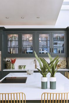 a kitchen with two vases on the counter and some chairs in front of it