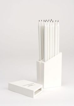 six white candles are in a box and one is empty