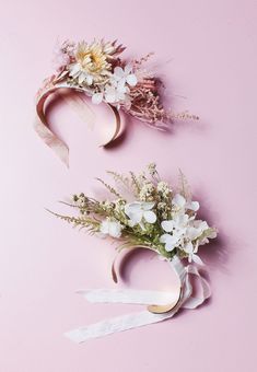 two pieces of paper with flowers and ribbons attached to them on a pink background,