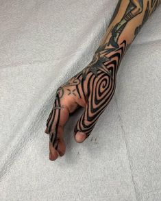 a person's arm with tattoos on it and a hand that has a spiral design