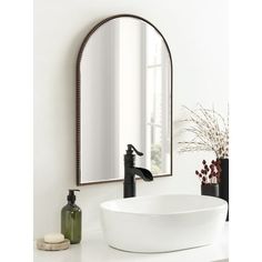 a bathroom sink sitting under a mirror next to a faucet and vase with flowers