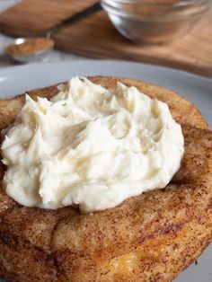 a piece of bread with whipped cream on it sitting on a plate next to a spoon